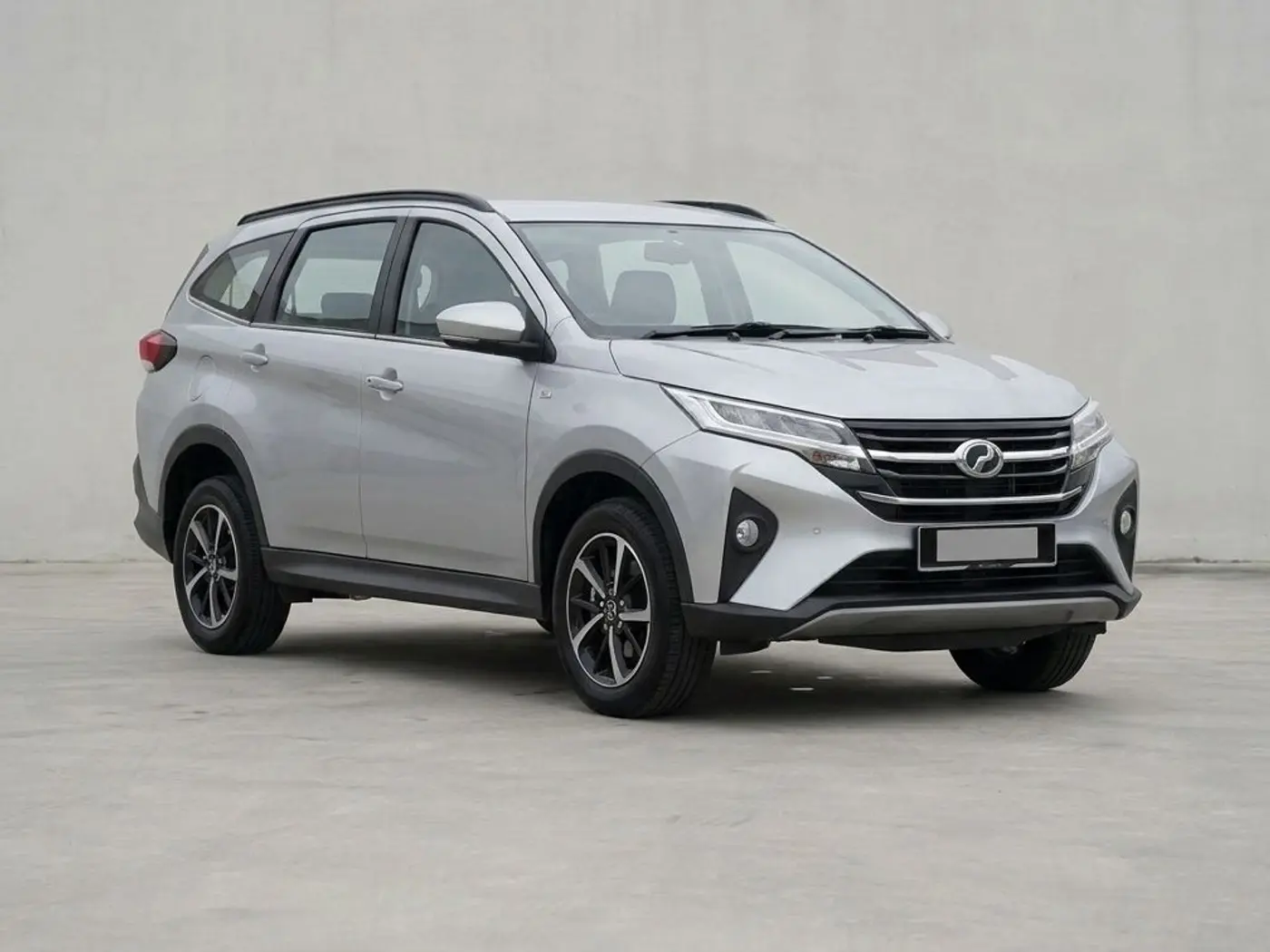 A silver Perodua Aruz seven-seat SUV on a concrete forecourt