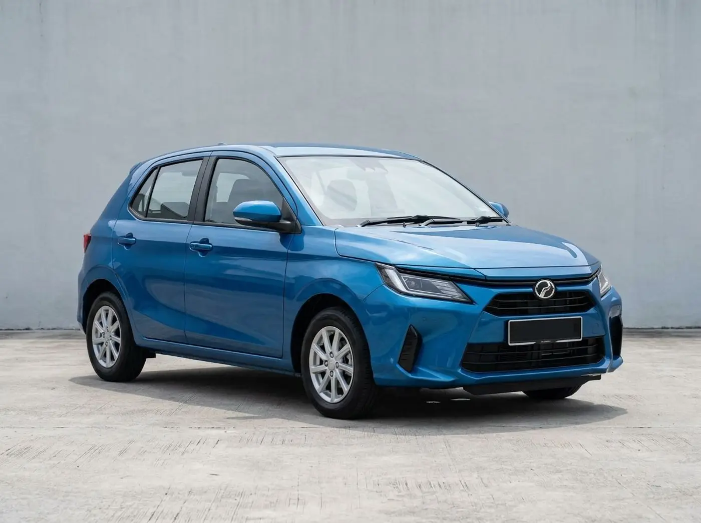 A blue Perodua Axia hatchback on a concrete forecourt