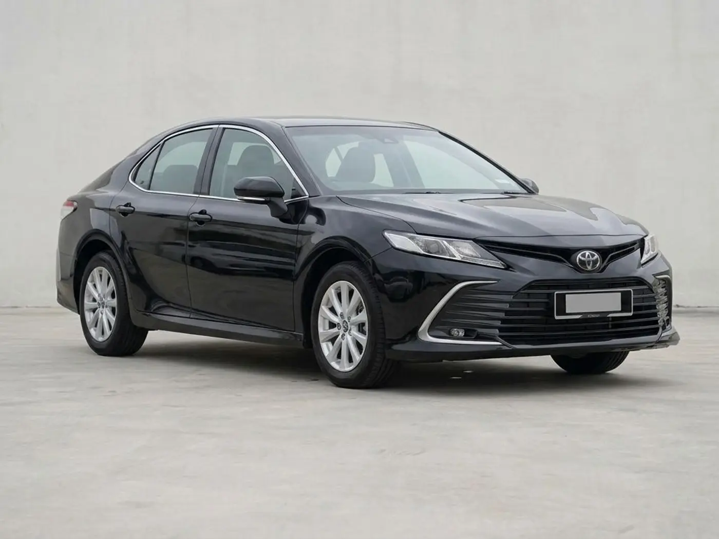 A black Toyota Camry sedan on a concrete forecourt