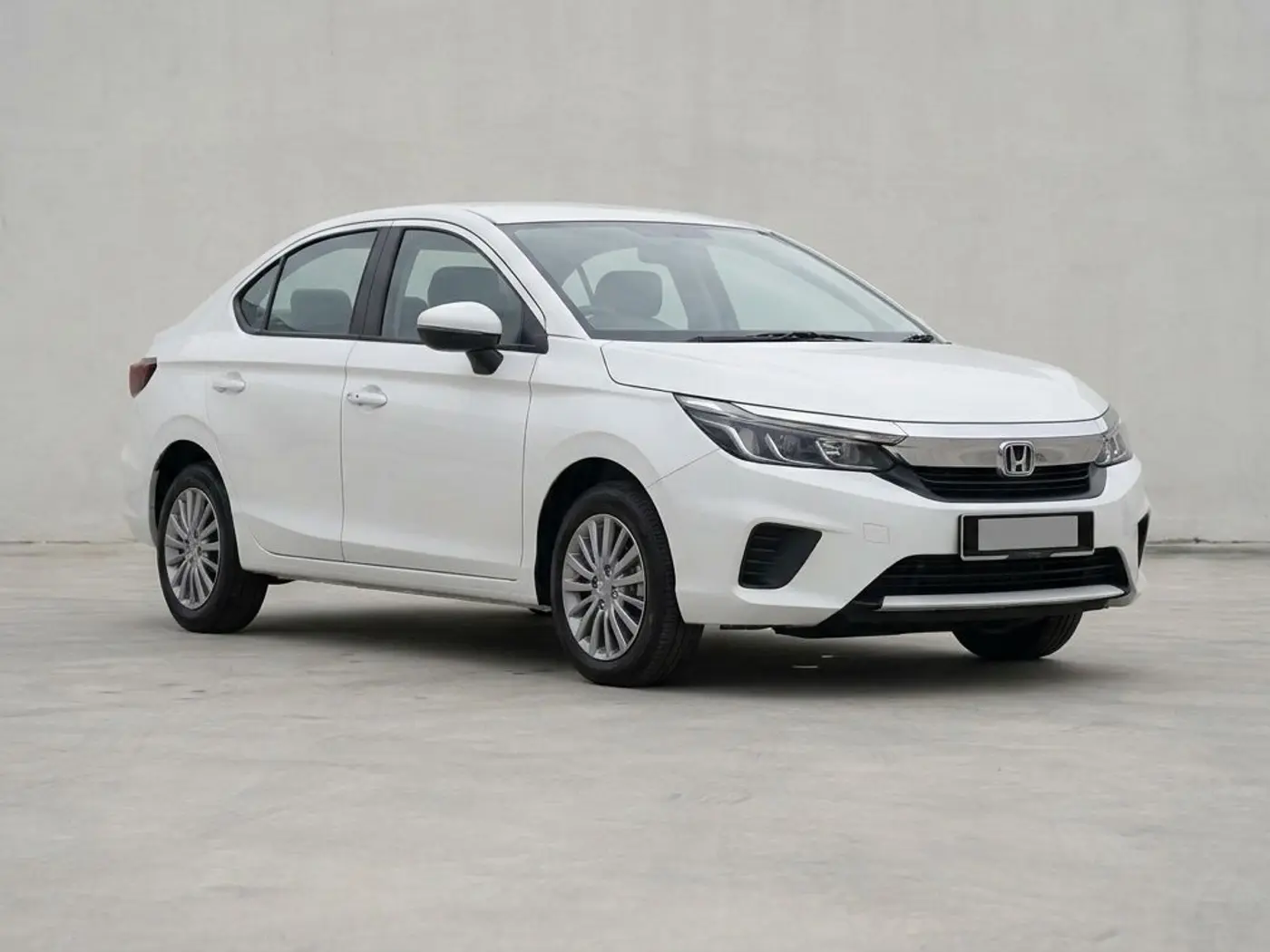 A white Honda City sedan on a concrete forecourt