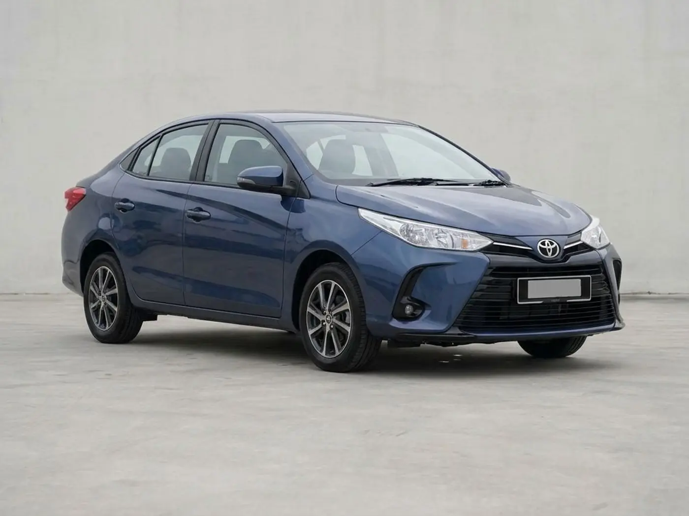 A dark blue Toyota Vios sedan on a concrete forecourt