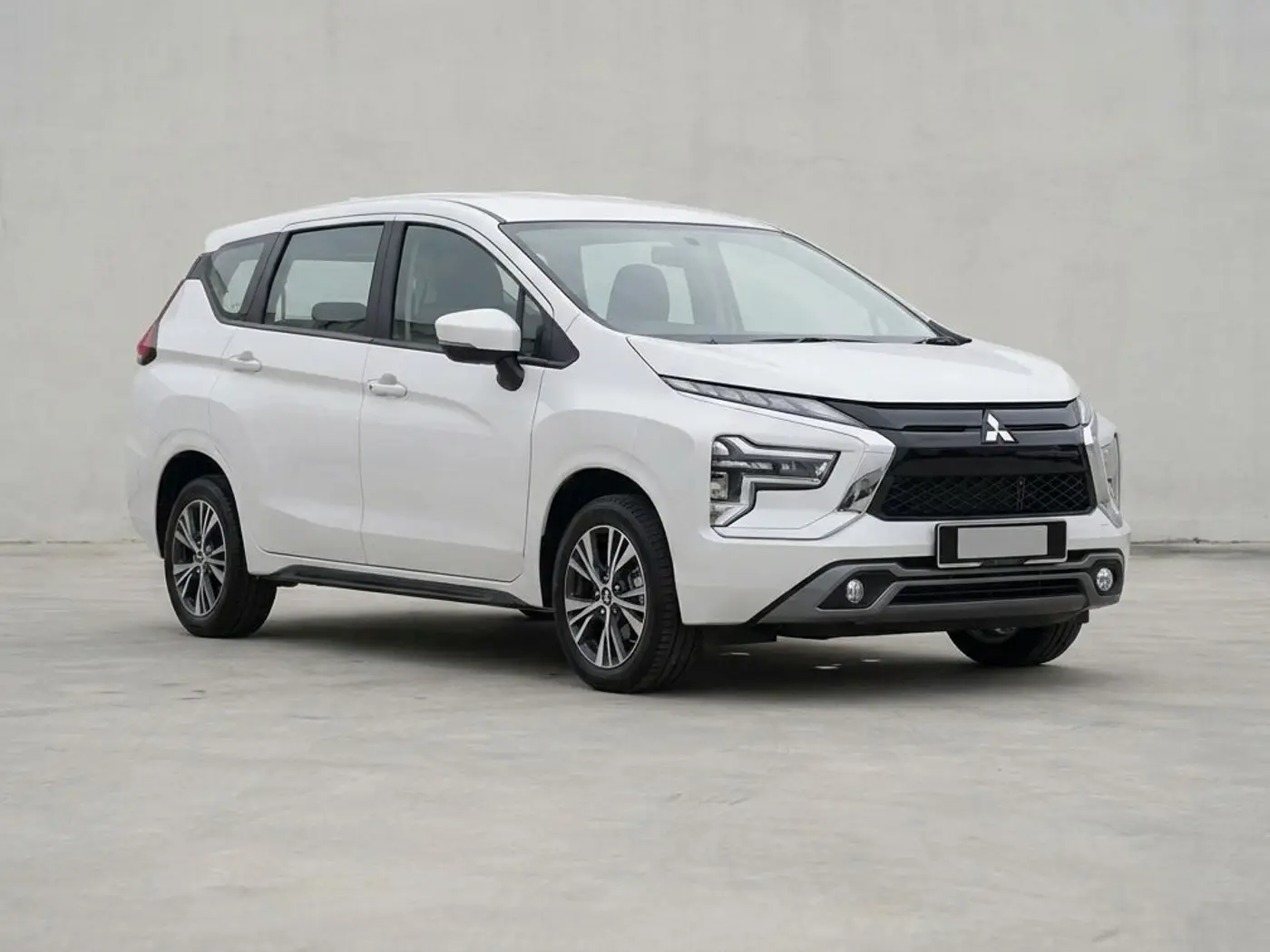 A white Mitsubishi Xpander seven-seater on a concrete forecourt